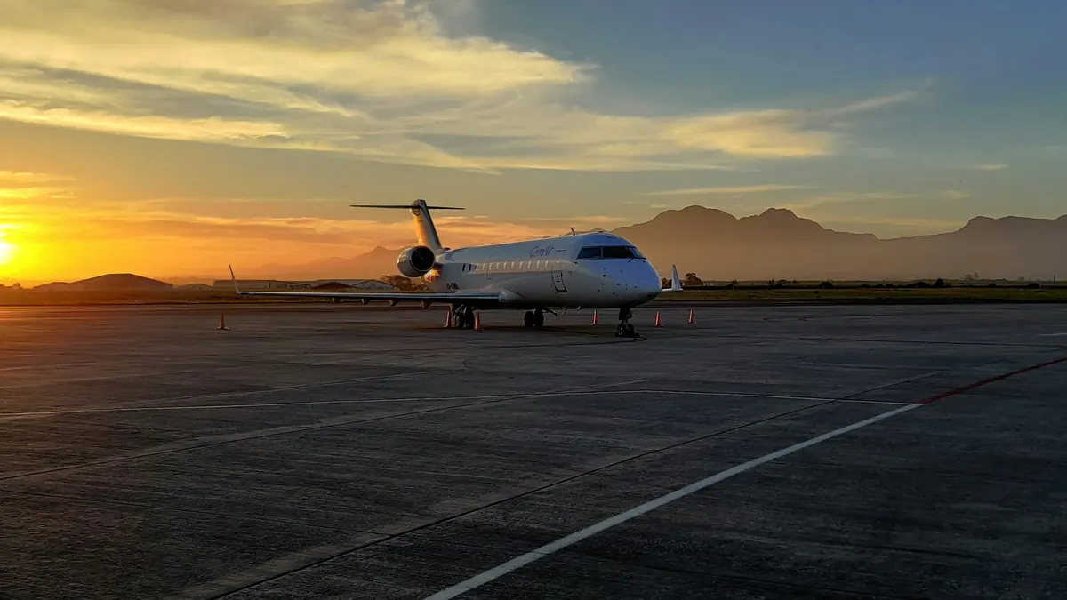 A private jet on the ramp at sunset with mountains behind